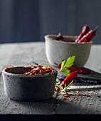 Chilli peppers in grey concrete bowls with parsley and rosemary