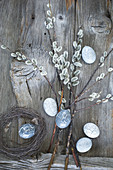 Grey-painted Easter eggs hung from pussy willow branches in bottle