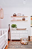 Chest of drawers below shelves in nursery in natural shades