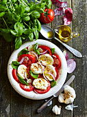 Tomatoes with mozzarella, red onions, olive oil and basil