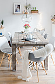 Grey and white shell chairs around rustic, shabby-chic wooden table