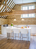 Open-plan kitchen below exposed roof structure in converted barn