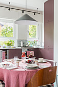 Set table in kitchen-dining room with dusky-pink cabinets