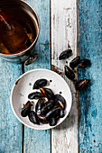 Raw Mussels Clams in vintage ceramic colander and Rose Wine in ice bucket on blue wooden background
