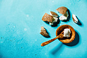 Bio-Kokosbutter und frische Kokosnuss in Stücken auf blauem Untergrund