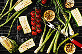 Grilled vegetables green asparagus, garlic, lemon, spring onion, zucchini, cherry tomatoes, salad on bbq grill rack over charcoal