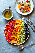 Früchte-Bowl arrangiert im Farbverlauf mit Minze-Orangensirup