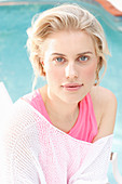 A blonde woman wearing a pink top and a white summer jumper