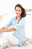 A brunette woman wearing a denim shirt and white trousers