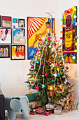 Christmas tree and presents in corner below comic-style artworks on wall