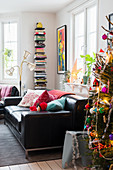 Christmas tree, black leather sofa, standard lamp and bookshelves in living room
