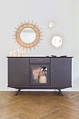 Arrangement of candles on sideboard below round mirror on wall