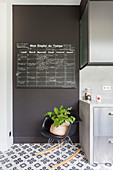 Chalkboard panel on black wall and classic rocking chair next to kitchen cupboards