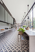 Long, narrow kitchen with concrete counter, cement tiles and glass wall