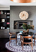 Round black table with walnut and leather chairs in front of a fireplace