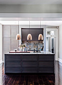Kitchen island with marble top, copper pendant lights above it, colorful tiles in the background as splash protection