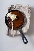 Brownie in a skillet with a scoop of vanilla ice cream, salted caramel and roasted peanuts