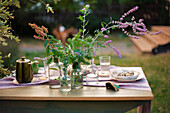 Flowers in apothecary bottles on set table in garden