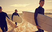 Three young men with surfboards in the sea