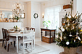 Weihnachtlich dekorierter Esstisch und geschmückter Weihnachtsbaum in skandinavischem Esszimmer