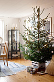 Decorated Christmas tree and gifts in front of display cabinet in living room