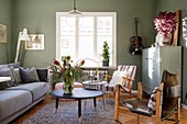 Polstersofa, Coffeetable und Armlehnstühle im Wohnzimmer mit grünen Wänden