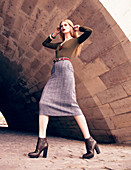 A blonde woman wearing a brown jumper and woollen skirt