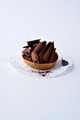 A miniature chocolate tartlet against a white background