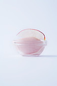 White peach sorbet in a glass bowl against a white background