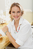 Blonde Frau in weißer Hemdbluse, bunte Perlenkette und Armband