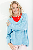 A blonde woman wearing a red top and a blue jumper
