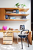 Desk with chair, wooden shelf above in the study