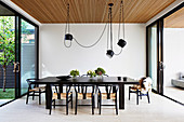 Dark dining table with classic chairs and pendant lights above the patio door