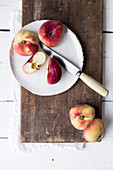 Peaches on a white plate with a knife on a white surface