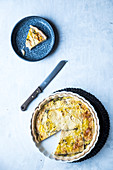 A quiche with a slice of on a plate on a white surface