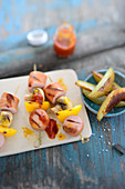 Curried sausage skewers with peppers and mushrooms served with potato wedges