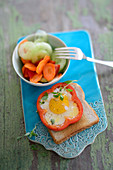 A fried egg flower on toast served with vegetable salad