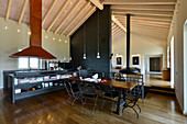 Essbereich und Küche mit riesigem Dunstabzugshaube, schwarzer Raumteiler in offenem Wohnraum