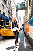 A young blonde woman wearing a black-and-white star hoodie, a gilet and jeans