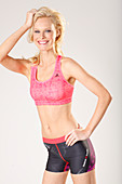 Junge blonde Frau in pinkfarbenem Sport-BH und Shorts