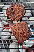Vegan burger patties over a charcoal grill (top view)