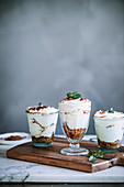 Tiramisu served in glasses on a wooden board and a marble table