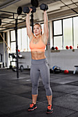 A young woman performing a thruster with dumbbells