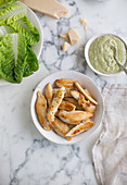 Salad ingredients: grilled chicken strips, lettuce leaves, parmesan and dressing