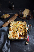 Lasagne in a dish, served with bread, wine and cheese