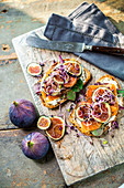 Salmon sandwiches with figs and sprouts on a wooden board