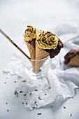 Chocolate cake topped with caramel cream and dark chocolate sprinkles served in ice cream cones (vegan)