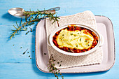 Lamb ragout with a potato topping garnished with thyme and rosemary