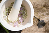 Making homemade chive-flower salt: grinding flowers and salt with mortar and pestle