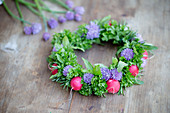 Handmade wreath of chive flowers, herbs and radishes